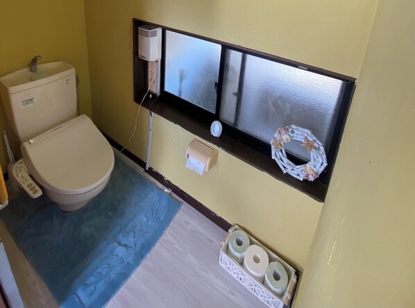 Un baño pequeño con un inodoro, un purificador de aire de pared, un dispensador de papel higiénico y un adorno decorativo.