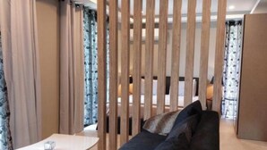 Un salon moderne avec un canapé foncé, une table basse blanche et un séparateur en bois.