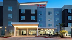 A modern hotel with a flat roof, large windows, and a sign reading "Townplace Suites by Marriott." - Towneplace Suites By Marriott Brownsville (Brownsville)
