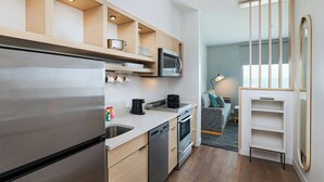 A modern kitchen with a stainless steel refrigerator, built-in microwave, and oven. There is a dishwasher and a coffee maker on the counter. - Towneplace Suites By Marriott Brownsville (Brownsville)