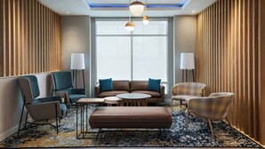 A modern hotel lobby with a sofa set, armchairs, a coffee table, and a patterned rug. - Towneplace Suites By Marriott Brownsville (Brownsville)