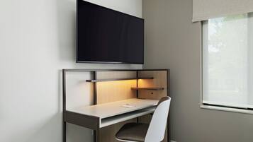 Una habitación de hotel moderna con escritorio, silla y un televisor de pantalla plana montado en la pared.