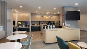 Una cocina moderna con una isla central, electrodomésticos integrados e iluminación colgante.