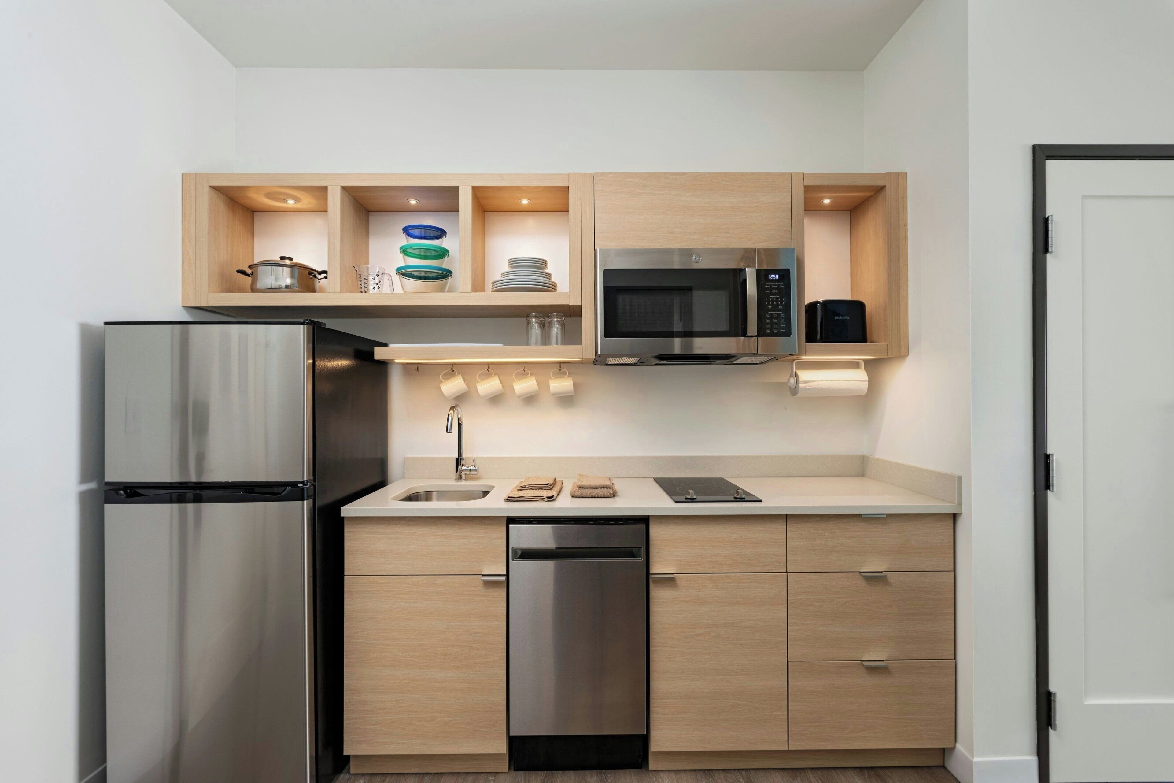 Una cocina compacta con un refrigerador de acero inoxidable, un microondas y un lavavajillas.