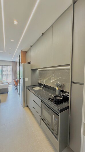 A modern kitchen with a built-in stove, a refrigerator, and a large window. - La Vida (São Paulo)