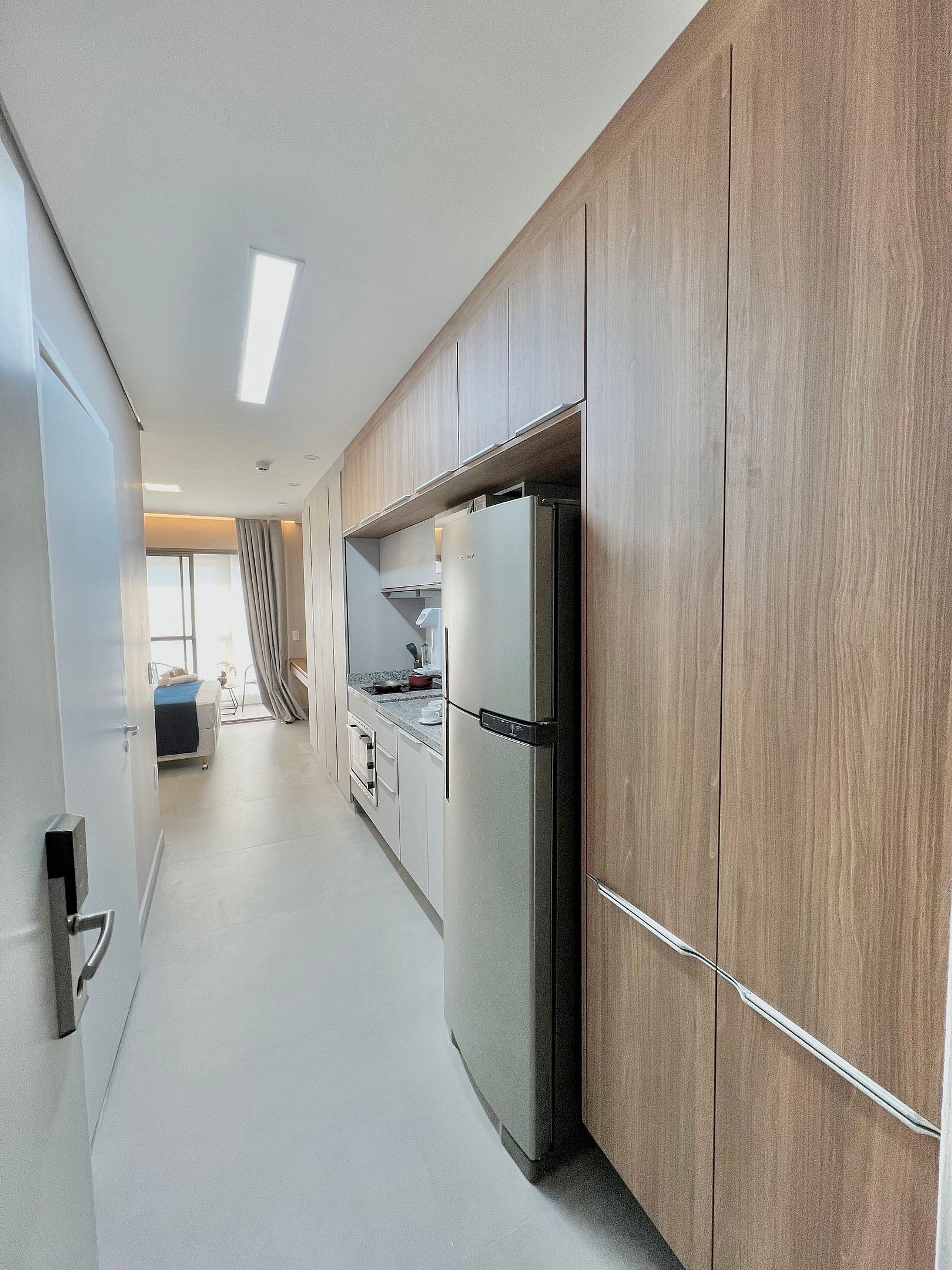 Una cucina moderna con mobili in legno, un frigorifero in acciaio inossidabile e una finestra che offre luce naturale.