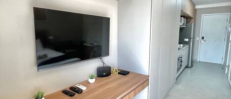 A modern kitchen with a built-in TV, wooden countertop, and a small plant.
