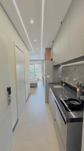 A modern kitchen with a black countertop, stainless steel appliances, and a view to a balcony. - La Vida (São Paulo)