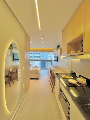 A modern kitchen with a dining area, a bed, and a view of buildings. - La Vida (São Paulo)