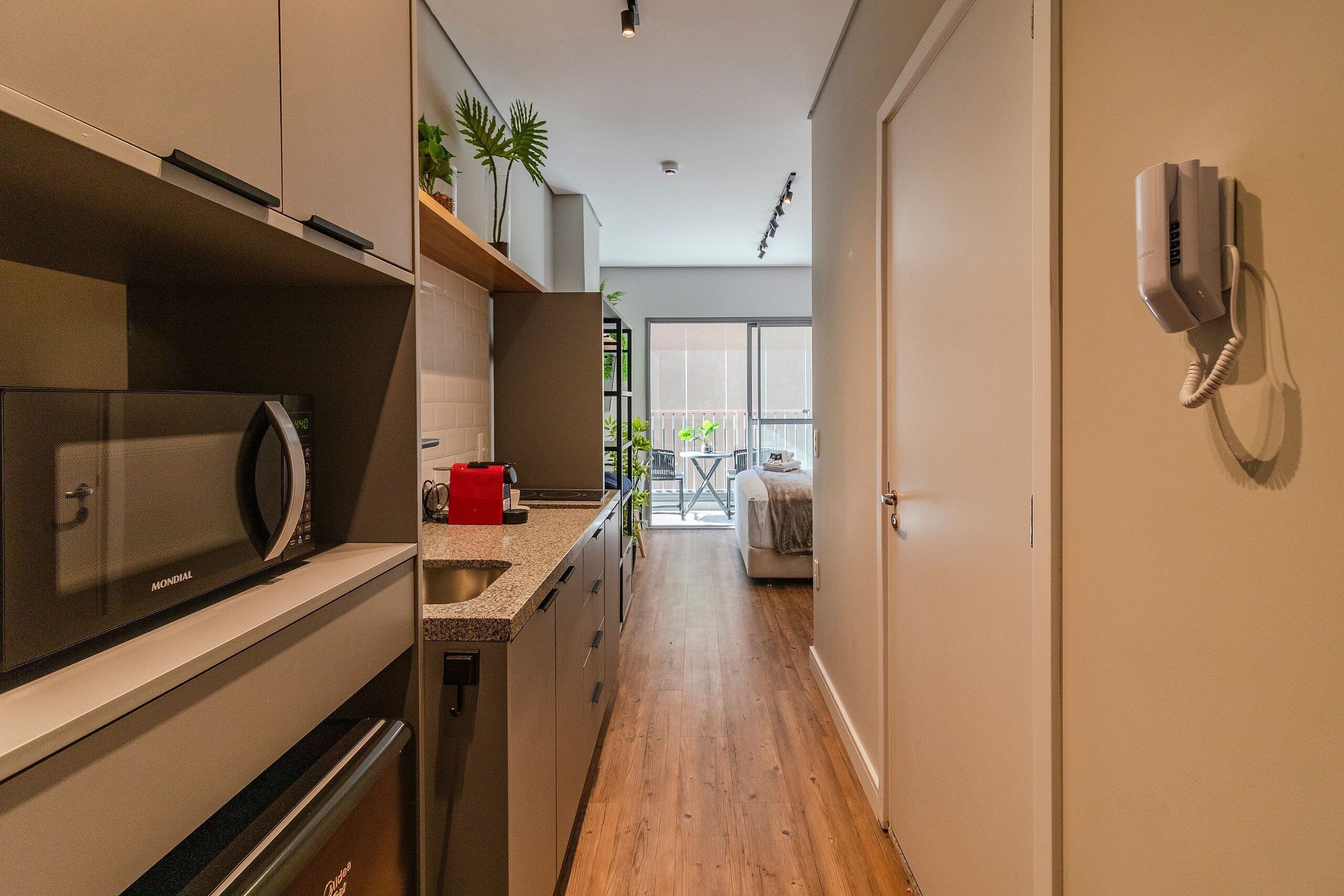 A modern kitchen with a built-in microwave and a red coffee machine.