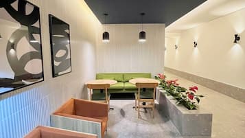 A modern interior with a green sofa, wooden chairs, and a long bench.