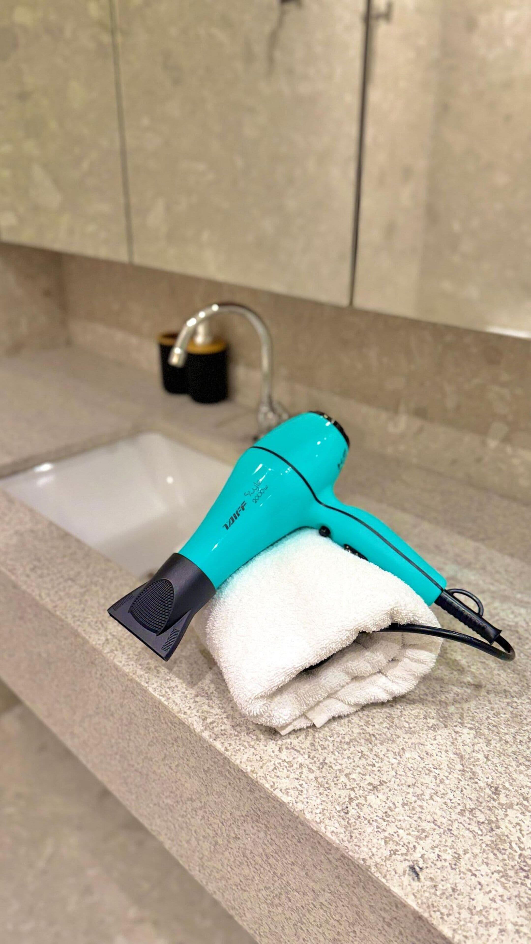 A bathroom with a sink, a towel, and a hairdryer on the countertop.