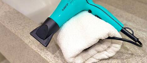 A bathroom with a sink, a towel, and a hairdryer on the countertop.
