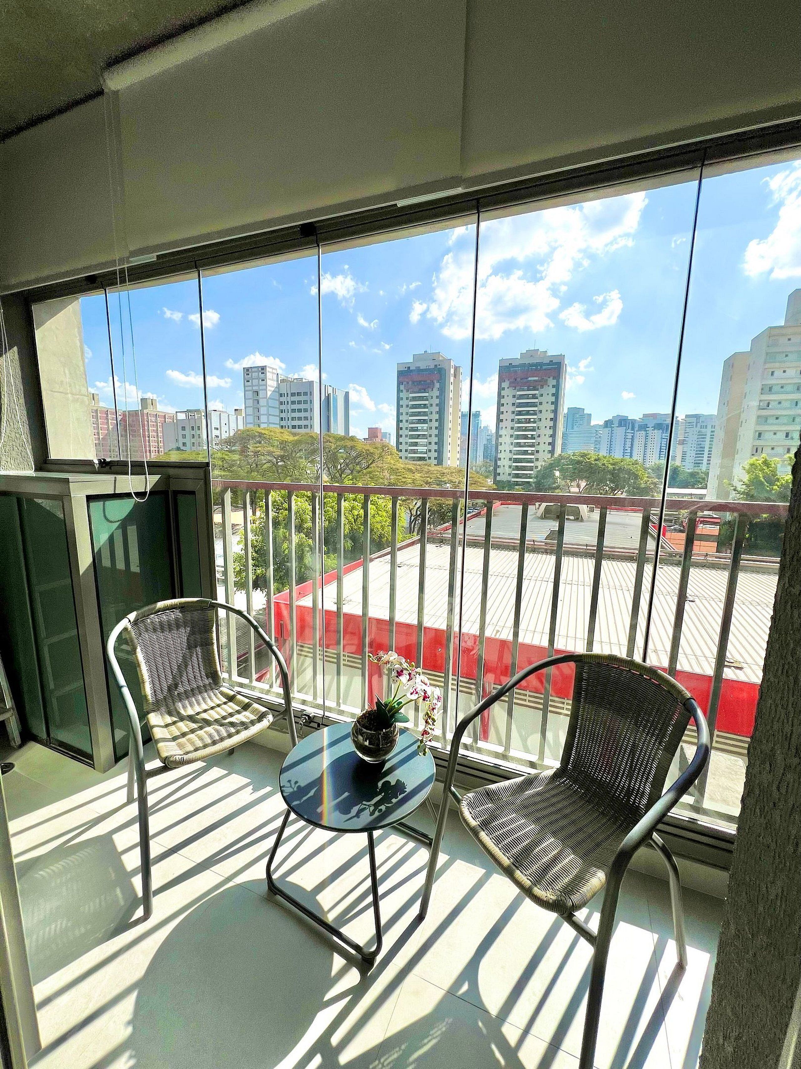 A balcony with two wicker chairs, a small table, and a potted plant.