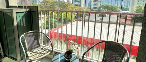 A balcony with two wicker chairs, a small table, and a potted plant.