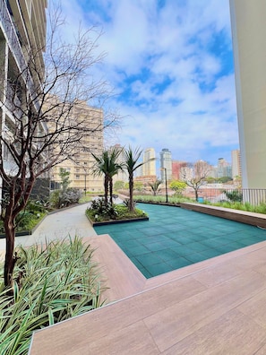 A rooftop garden with a pool, surrounded by buildings and clear skies. - La Vida (São Paulo)