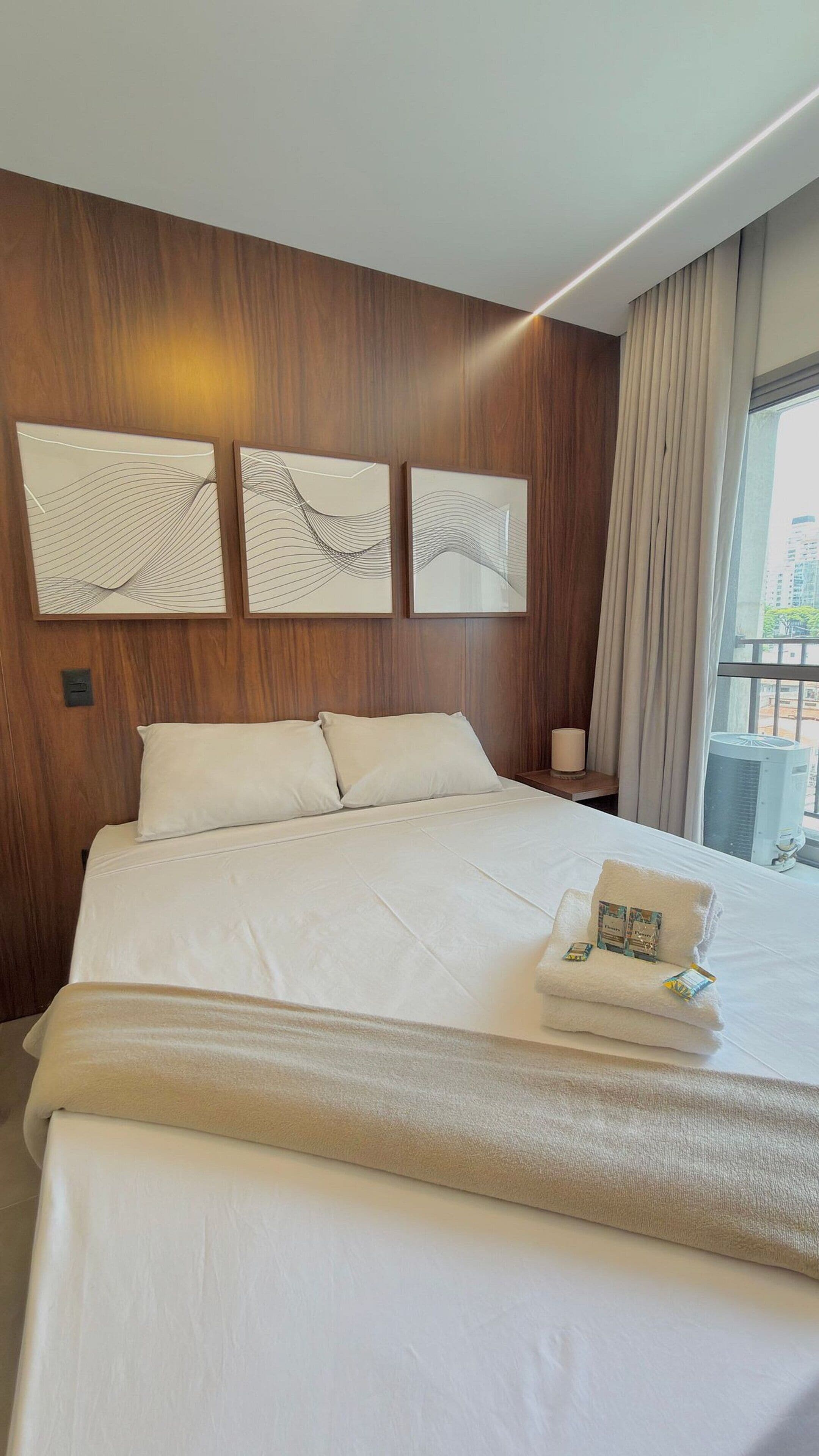 Ein Hotelzimmer mit einem großen Bett, Holzvertäfelung an den Wänden und drei Wandbildern.