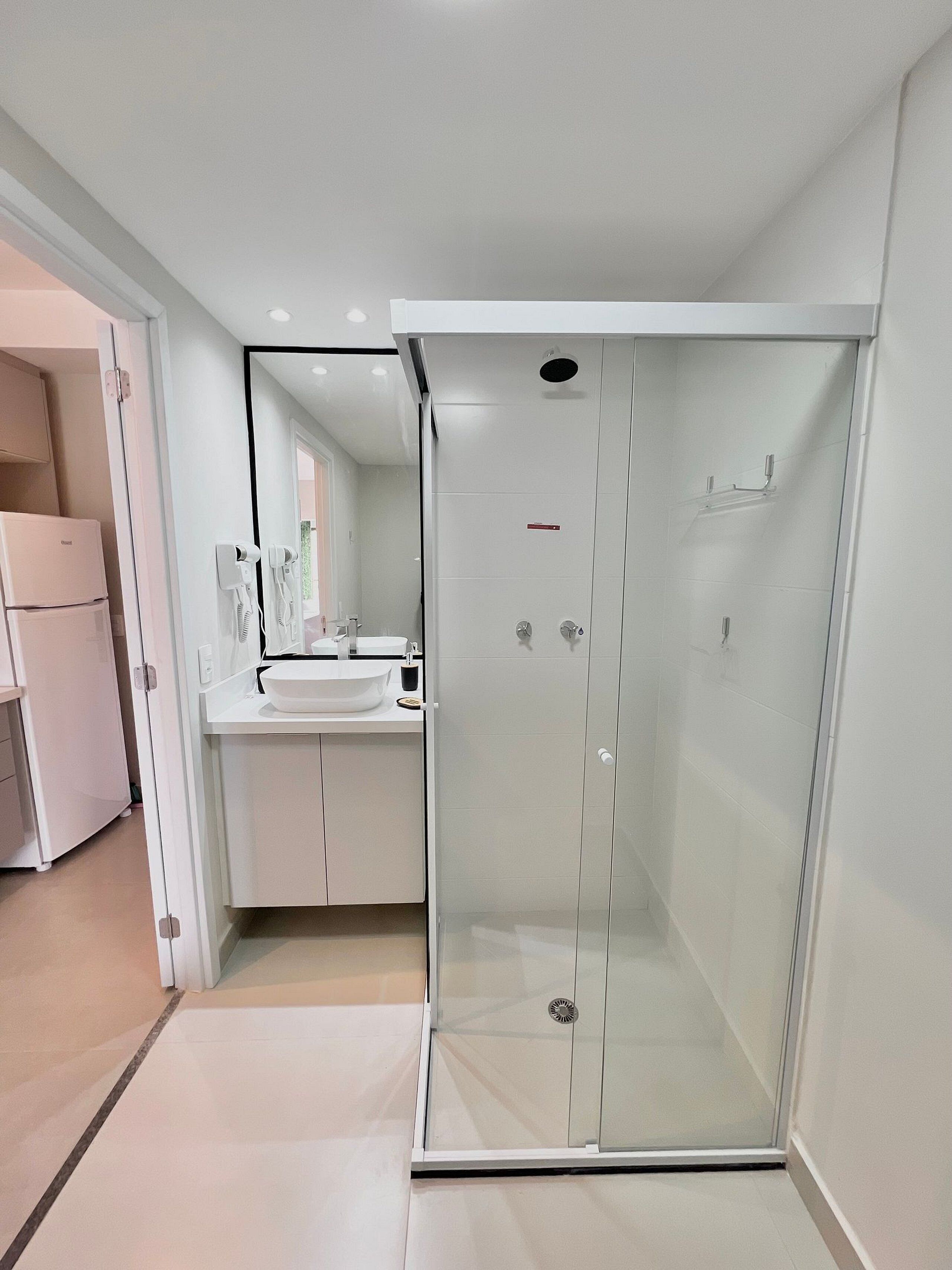 Une salle de bain moderne avec une douche à parois de verre, un lavabo blanc et un miroir.
