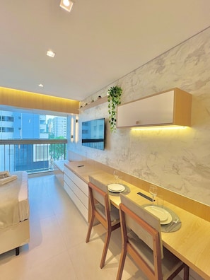 Una cocina moderna con una isla grande, sillas de madera, una mesa de comedor y un televisor montado en la pared.