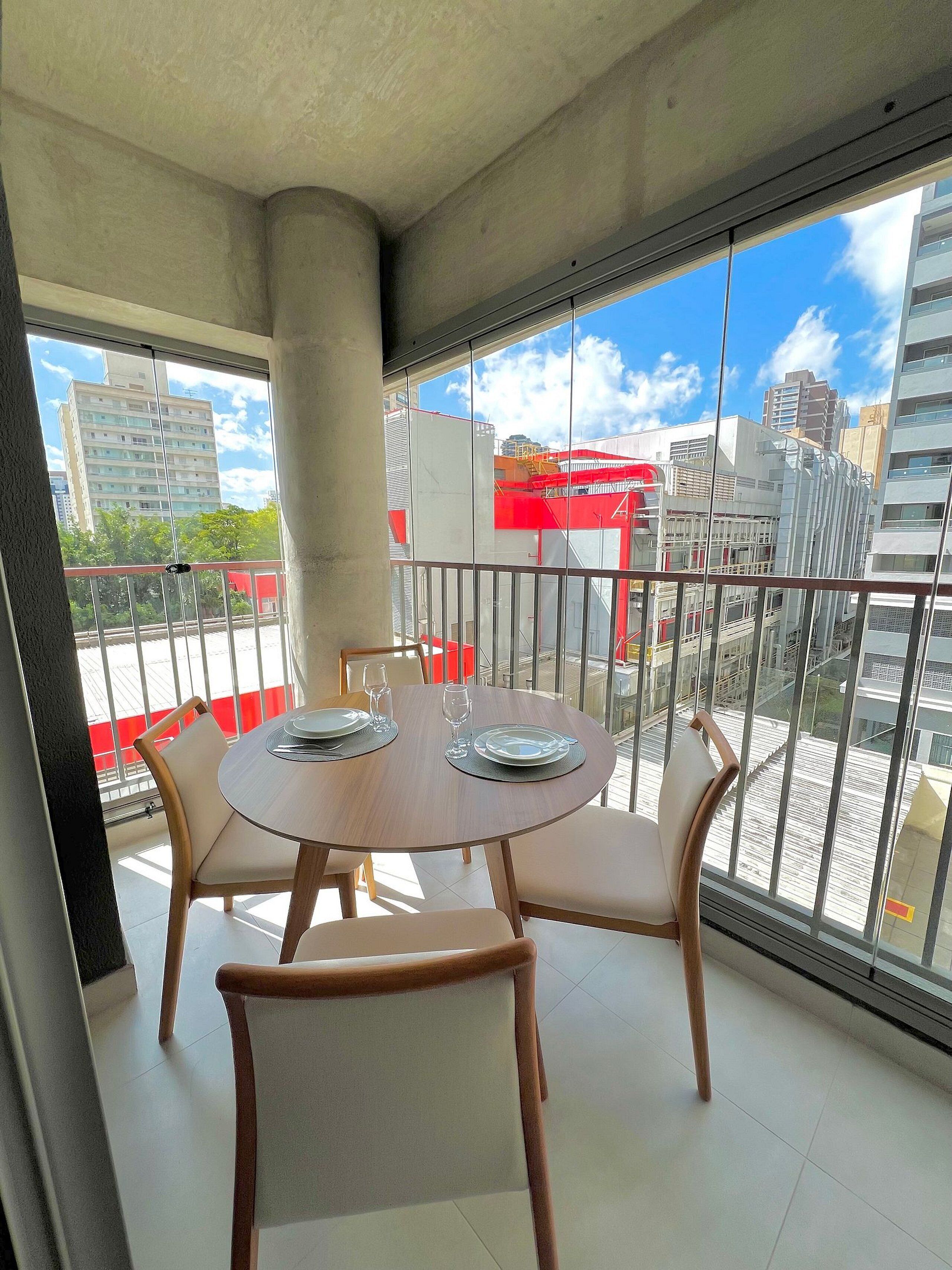 A balcony with a round table, four chairs, and a view of the cityscape.