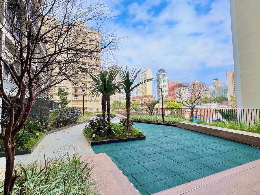 A rooftop garden with a pool, surrounded by buildings and clear skies.