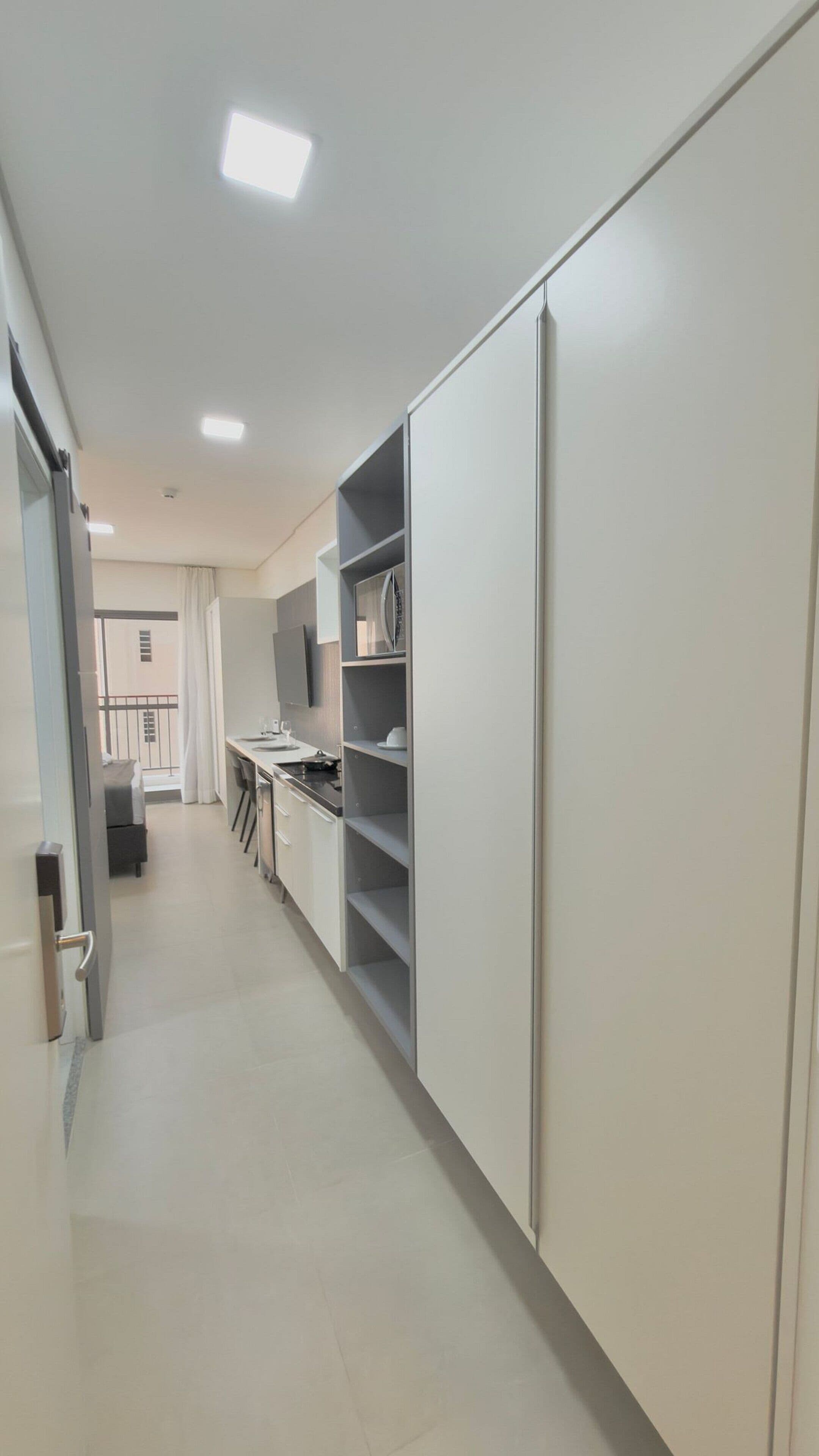 A modern kitchen with white cabinets, a dining area, and a view of the balcony.