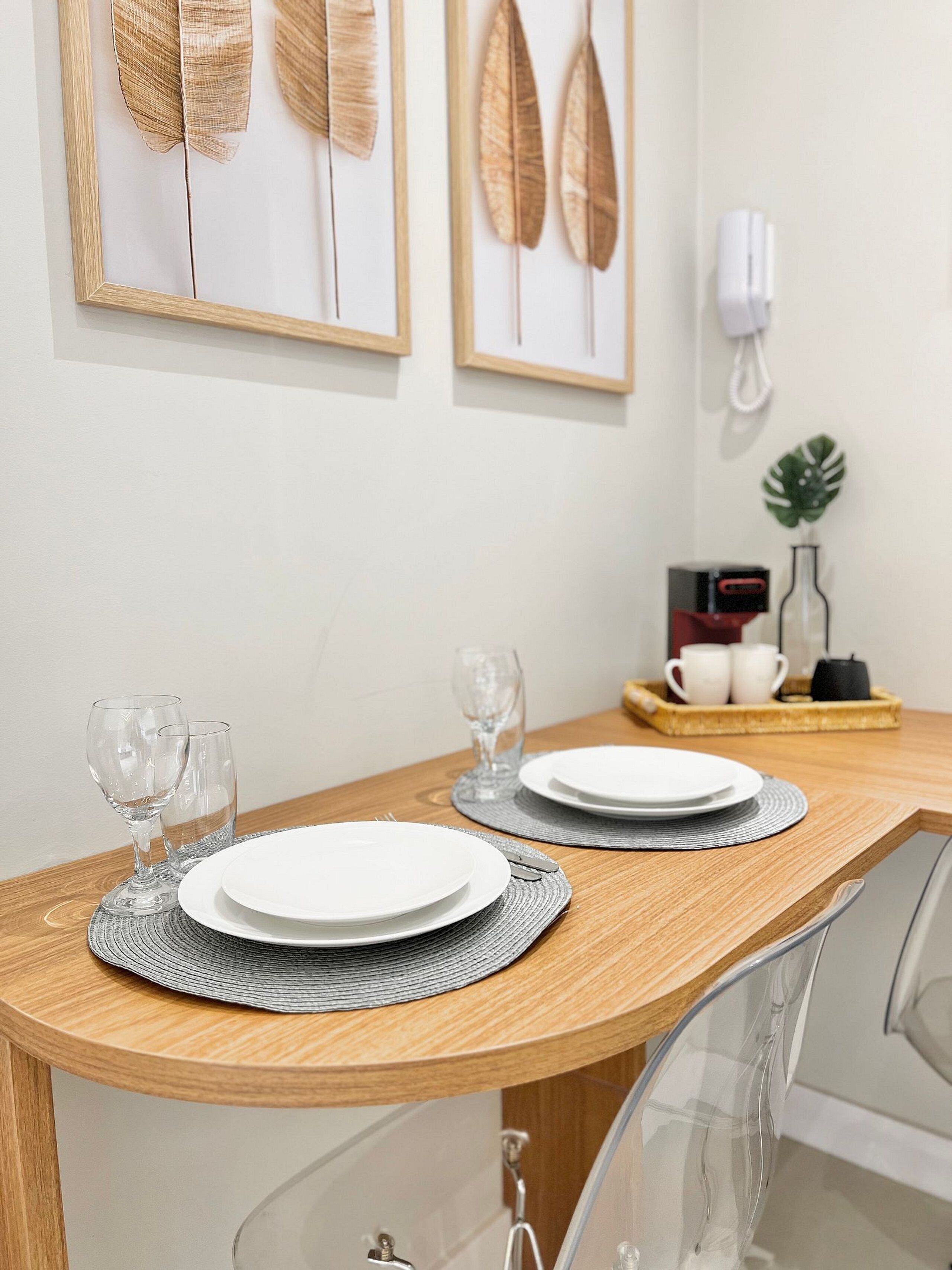 A dining table with plates, glasses, and a tray with cups and a kettle.
