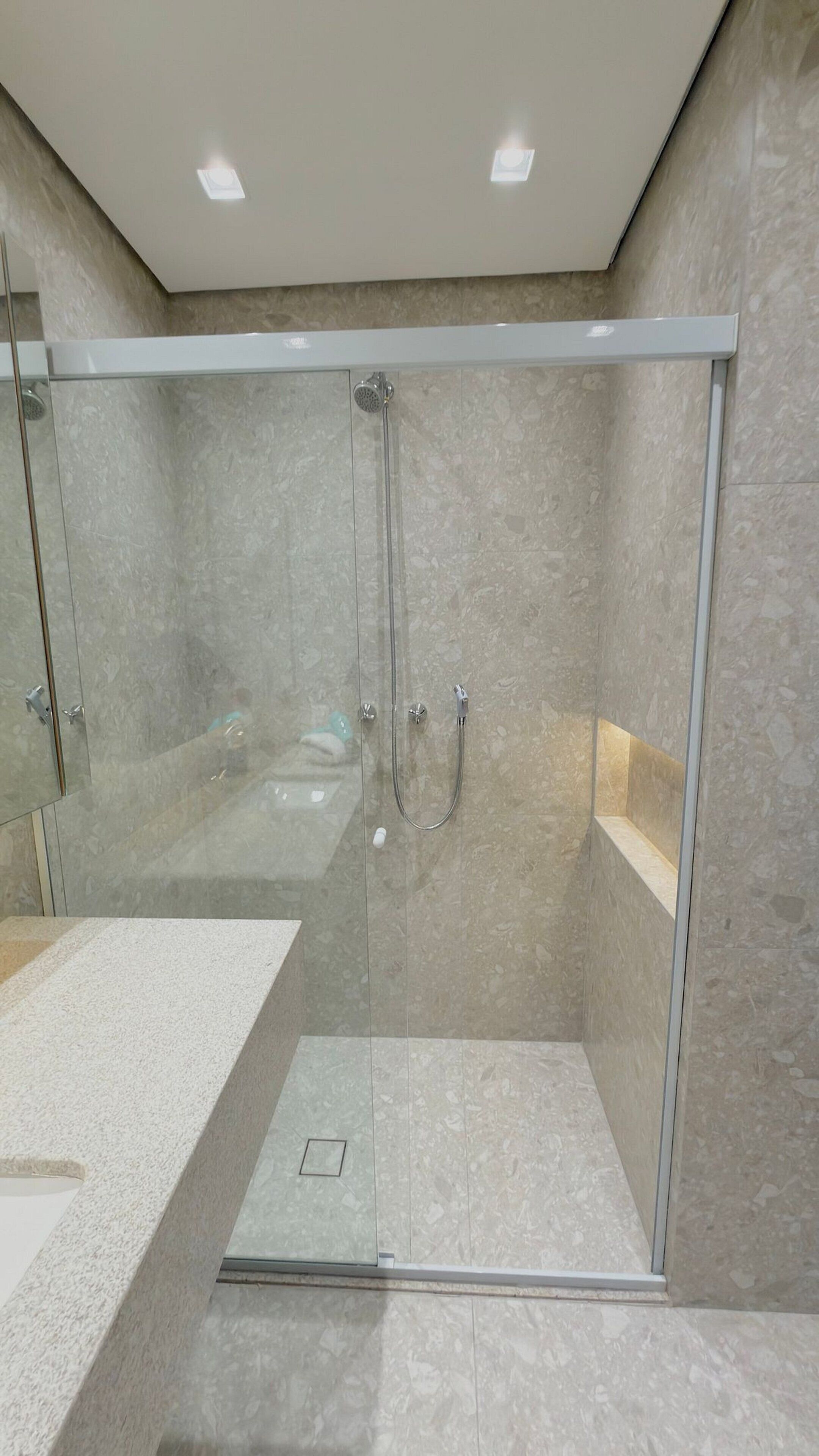 A modern bathroom with a glass-enclosed shower, a bathtub, and a vanity with a countertop.
