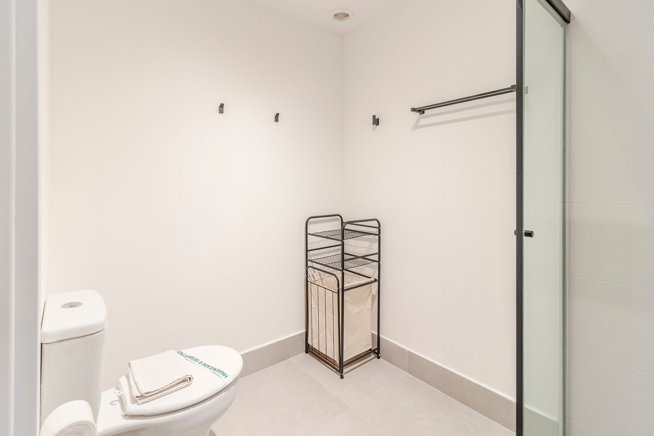 A bathroom with a toilet, a towel rack, and a glass shower enclosure.
