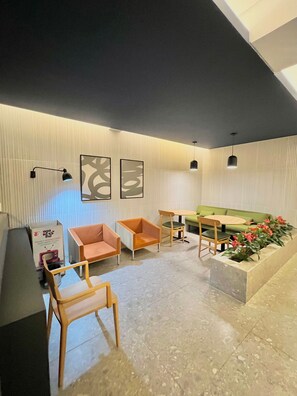 A modern lounge area with a sofa, chairs, a small table, and a planter with flowers. - La Vida (São Paulo)