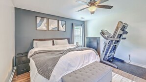 A bedroom with a bed, a treadmill, and a ceiling fan. - Charming Charleston Escape (North Charleston)