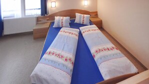 Un lit double avec une literie à motifs floraux, une tête de lit en bois et une table de chevet.