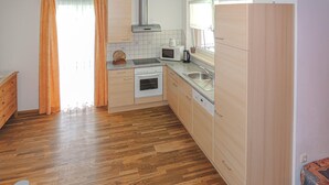 Une cuisine compacte dotée de meubles en bois, d’un four à micro-ondes, d’une bouilloire et d’un lave-vaisselle.