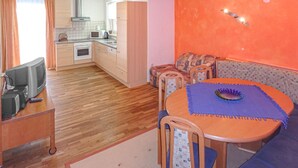 Une cuisine compacte équipée d’un four à micro-ondes, d’une cuisinière et d’un évier. Un coin repas avec une table et des chaises est situé à côté de la cuisine.