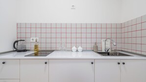 A modern kitchen with white cabinets, a stainless steel sink, and a grid-patterned backsplash. - Cozy studio with WiFi and AC in charming T'bilisi (T'bilisi)