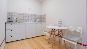 A compact kitchen with white cabinets, a small countertop, a kettle, and a table with chairs. - Cozy studio with WiFi and AC in charming T'bilisi (T'bilisi)