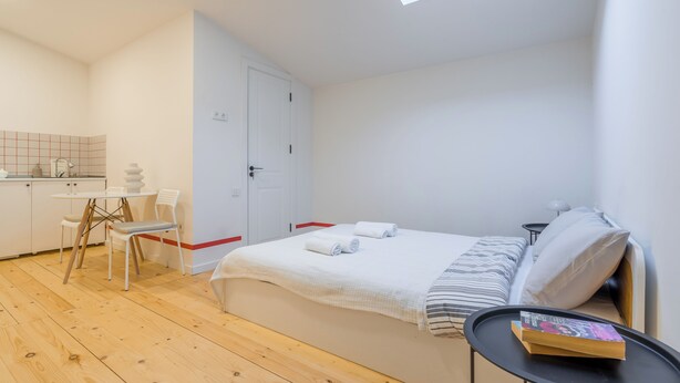 A bedroom with a bed, a bedside table, a chair, and a small table with a book. - Cozy studio with WiFi and AC in charming T'bilisi (T'bilisi)