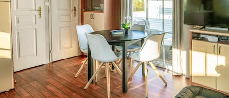 A dining area with a table and chairs, a television, and a cabinet with a television.
