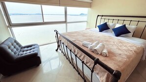 Habitación de hotel con una cama grande, una silla y vista al mar.
