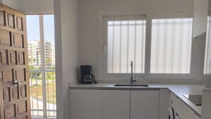 Eine moderne Küche mit Waschmaschine, Kaffeemaschine und einem Fenster mit Jalousien.