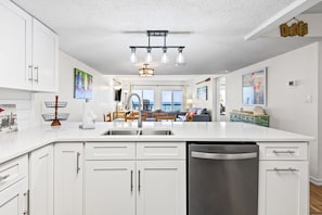 A modern kitchen with white cabinetry, a stainless steel dishwasher, and a central island with a sink. - Beachfront Charm Meets Lake Life + Free Tickets: Dolphin Cruise & More! (Panama City Beach)