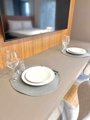 Mesa de jantar bem posta com dois pratos, duas taças de vinho e um garfo.