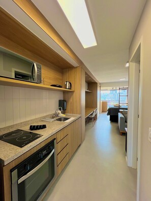 A modern kitchen with built-in appliances, a dining area with a sofa, and a view of the city. - Innvista -Trends Brooklin. (São Paulo)