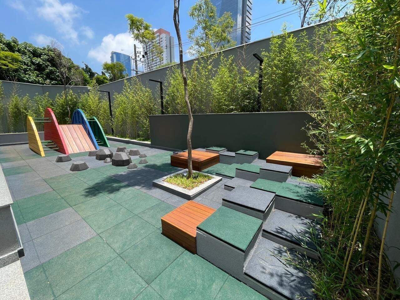 Un giardino pensile con zone relax, un piccolo albero e un'area giochi.