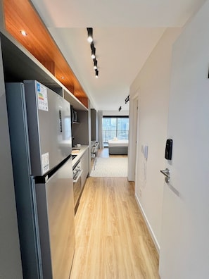 A modern kitchen with a built-in refrigerator, wooden cabinets, and a view of the city through large windows. - Innvista -Trends Brooklin. (São Paulo)