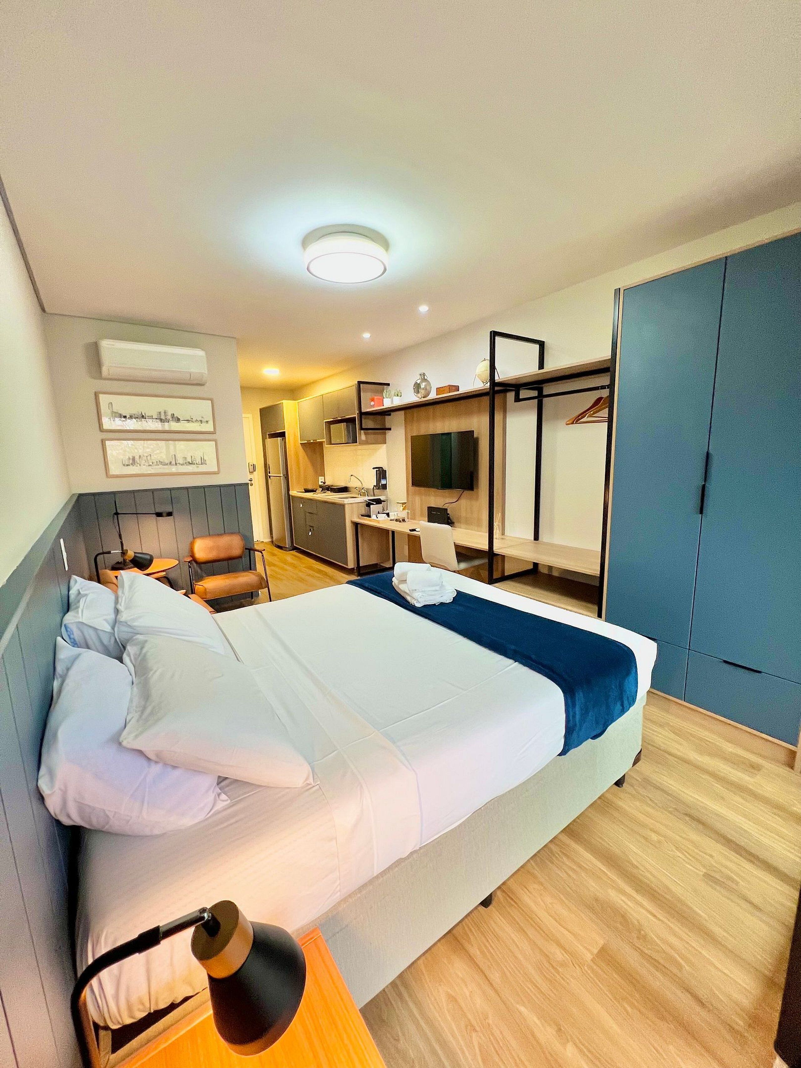 Camera d'albergo con un letto, una lampada da comodino e un angolo cottura dotato di forno a microonde e macchina per caffè.
