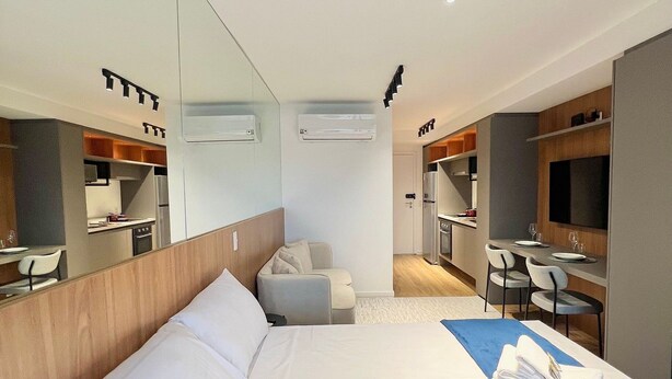 A hotel room with a large bed, a desk, a chair, a sofa, and a TV. - Innvista -Trends Brooklin. (São Paulo)