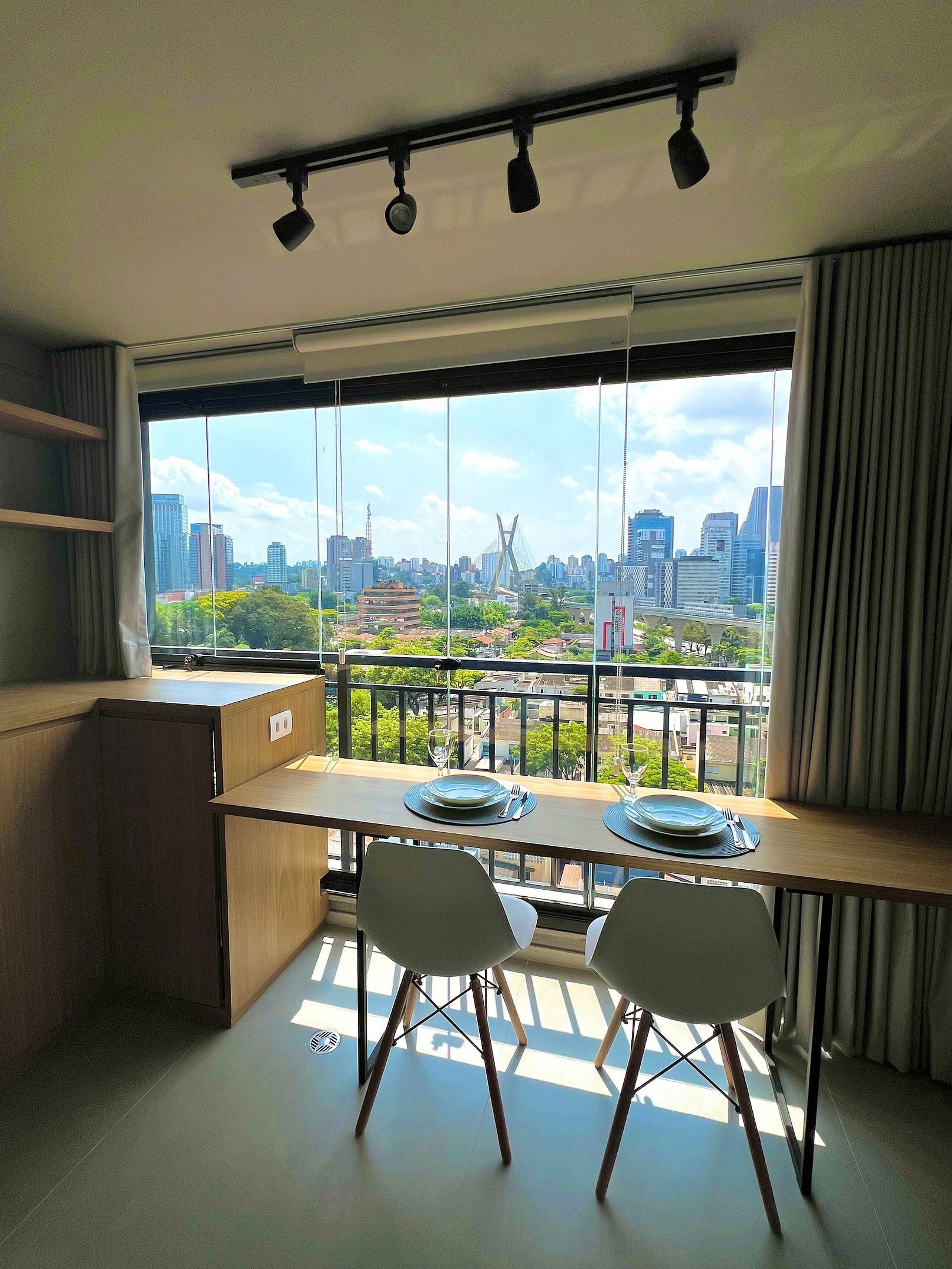 A modern kitchen with a dining area overlooking a cityscape.