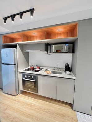 Cozinha moderna com forno embutido, micro-ondas e máquina de café sobre a bancada.