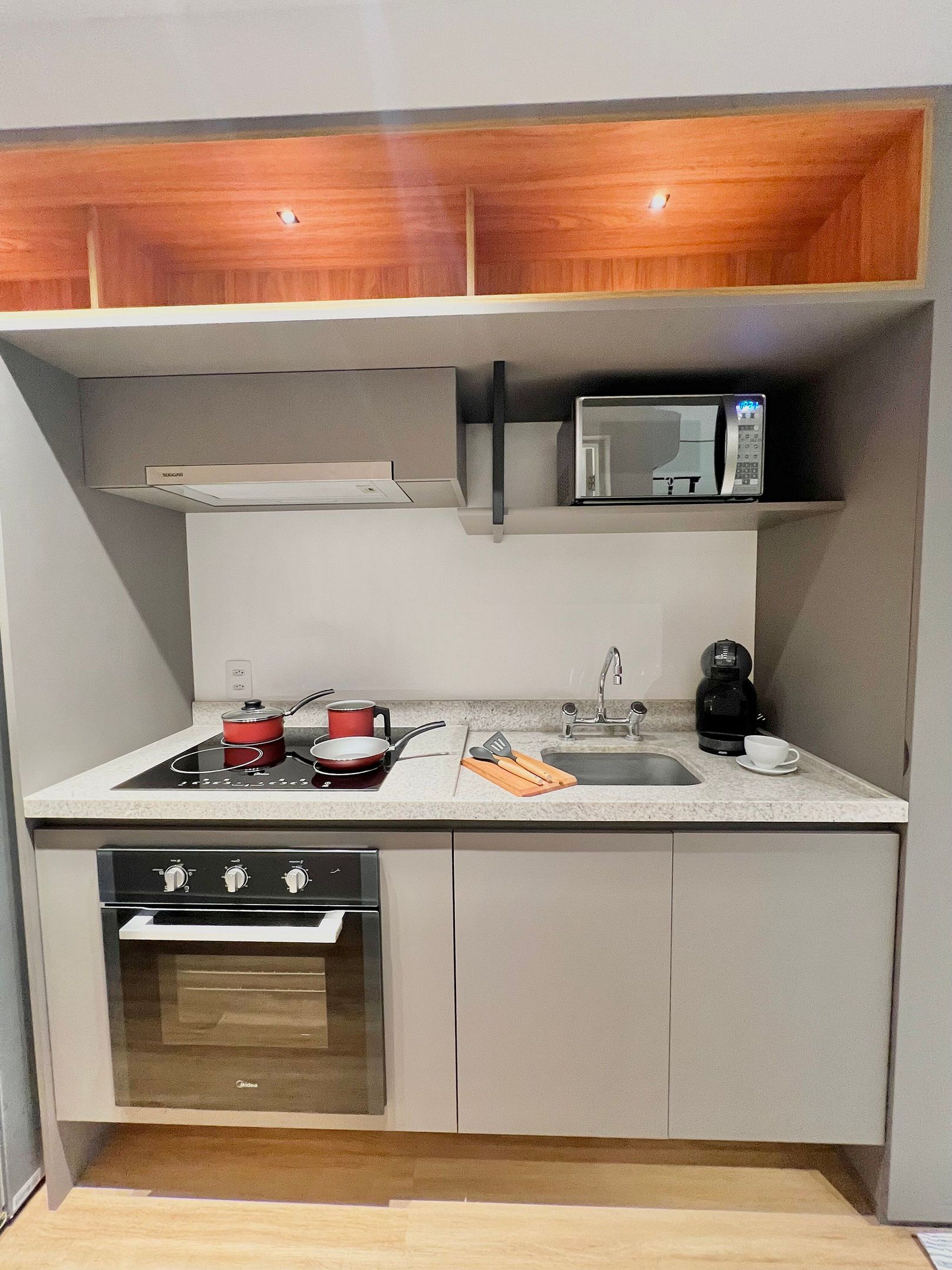 Una cucina compatta con forno a microonde, fornello e lavello.